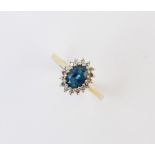A blue topaz and diamond cluster ring, the central oval topaz measuring 7mm x 5mm, with a cluster
