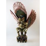 A large Indonesian polychrome painted carved figure of Garuda, modelled on a base realistically