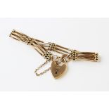 A 9ct gold gate link bracelet, 19cm long, suspending a 9ct gold heart-shaped padlock fastener and