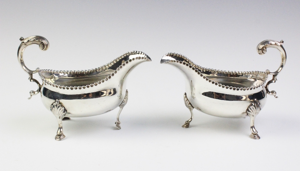A pair of George III silver sauce boats, each of oval form with leaf-capped scroll handle, punch