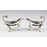 A pair of George III silver sauce boats, each of oval form with leaf-capped scroll handle, punch