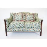 An Edwardian three piece lounge suite, the two seater sofa with a padded serpentine back rest