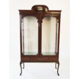 An Edwardian display cabinet, with arched moulded pediment above a pair of shaped glazed doors
