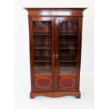 An Edwardian mahogany display cabinet, the moulded cornice above a frieze inlaid with chevron