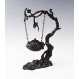 A Chinese bronze hanging koro and cover, designed as a blossom suspending a koro of compressed
