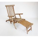 A teak steamer chair, late 20th century, of slatted form with brass fittings and a folding foot rest