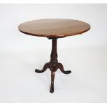 A George III oak tripod table, the circular top upon a bird cage movement and a baluster stem,