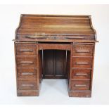 An early 20th century oak roll top desk, the 'S' form tambour front enclosing a compartmentalised