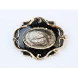 A Victorian mourning brooch, comprising a central transparent compartment containing hair, set to