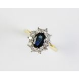 A sapphire and diamond cluster ring, comprising a central oval faceted sapphire measuring 7mm x 5mm,