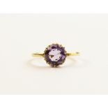 An amethyst coloured stone set 18ct gold ring, comprising a central round mixed cut purple
