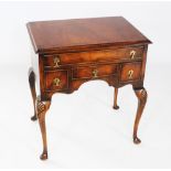 A George II style walnut low boy, circa 1930, the rectangular cross banded top above an