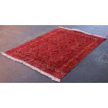 A Bokhara style carpet, the red ground with twelve lozenge shaped medallions punctuated by floral