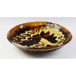 A large slipware shallow bowl, 18th century, the bowl with abstract patterned trailed slip