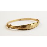 A George V 9ct gold hinged bangle, Chester 1911, the tapered front section with engraved foliate
