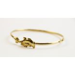 A 9ct gold dolphin bangle, the central motif moulded as two dolphins, 27mm x 11mm, set to a plain
