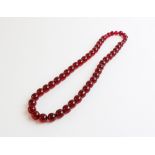 A cherry amber coloured beaded necklace, comprising fifty-one round polished beads of assorted sizes