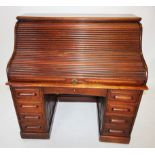 An early 20th century oak roll top desk, the 'S' shaped tambour front enclosing a