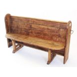 A Victorian pitch pine church pew, with moulded arched end supports enclosing the board seat and