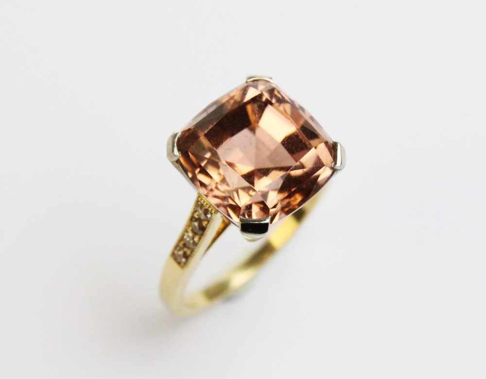A tourmaline and diamond ring, comprising a central pinkish-orange square cushion cut tourmaline