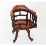 An early 20th mahogany revolving desk chair, the padded leatherette top rail raised upon incised