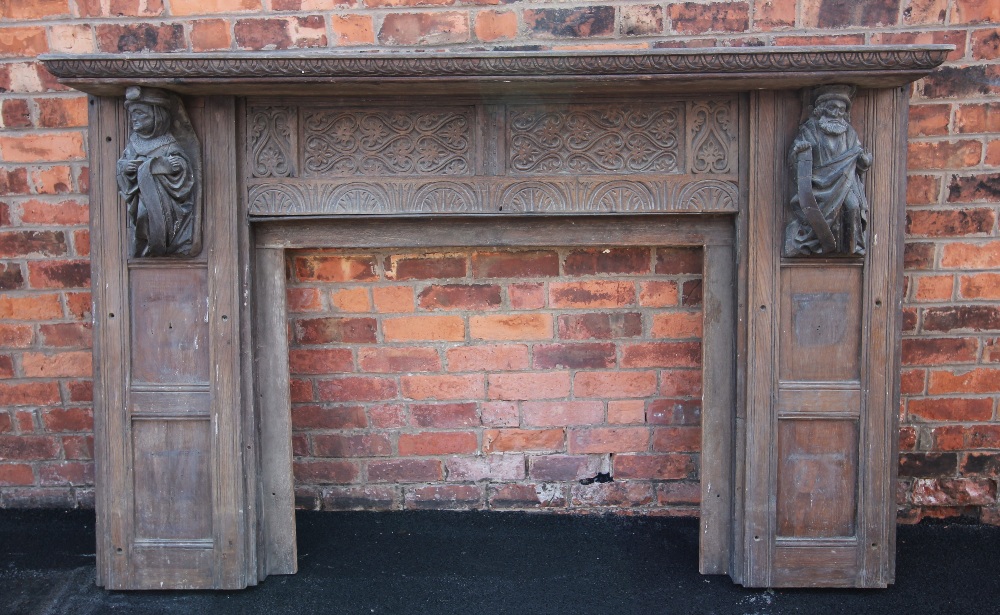 A 17th century style carved oak fire surround, 19th century, the rectangular shelf above panels