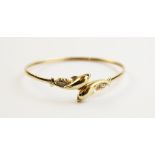 A 9ct gold diamond set dolphin bangle, designed as two dolphins upon waves, each set with a small
