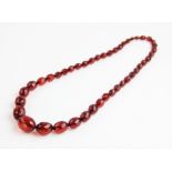 An cherry amber bead necklace, comprising forty-three oval faceted amber beads measuring between