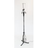 An early 20th century wrought iron standard lamp, the iron upright with twist detail extending to