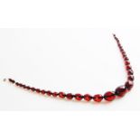 A cherry amber bead necklace, comprising thirty-four graduated faceted beads measuring between