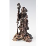 A Chinese carved hardwood figure of Shou Lao, modelled standing on an outcrop supported by a staff