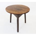 A late 18th century oak cricket table, the circular four plank top top raised upon three chamfered