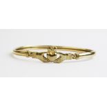 A 9ct gold claddagh bangle, of oval form with the central section design as two hands clasping a