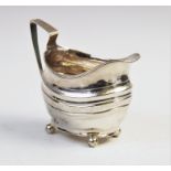 A George III silver cream jug, of oval form on four ball feet with engraved decoration to border and