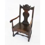A 17th century oak commode chair, the carved scrolling crest rail above a vase shaped splat and a
