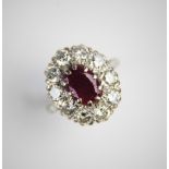 A ruby and diamond cluster ring, comprising a central oval mixed cut ruby measuring 11mm x 8mm, claw