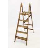 An early 20th century step ladder, of typical 'A' form, with painted iron hinges and a slatted top