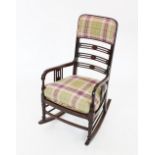 An Edwardian mahogany rocking chair, with a padded back rest above a pierced ladder back and a