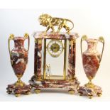 A late 19th century French rouge marble four glass clock garniture, the architectural marble case