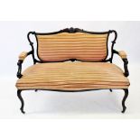 An Edwardian mahogany two seater settee, the shaped padded back below a carved foliate crest