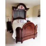 A Victorian mahogany half tester bed, the arched moulded canopy with floral drapes enclosing the