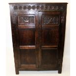 A 17th century style oak hall cupboard, with a carved repeating flower head frieze