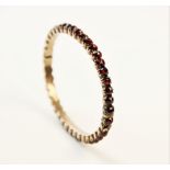 A 19th century garnet set bangle, designed as a single row of forty rose cut garnets, all claw set