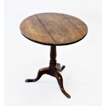 A George III oak tripod table, the circular three plank top raised upon a slender baluster and