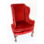 A George III style wing back fireside armchair, red velour with applied rope piping, the shaped wing