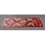 A large full pile black ground Iranian runner, with a floral medallion design, 383cm x 115cm