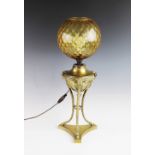 An early 20th century brass oil lamp, converted to electricity, the amber glass shade above a