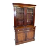 A late Victorian walnut library bookcase, with a moulded cornice above a pair of glazed cupboard