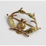 A 9ct gold ruby set owl brooch by Cropp & Farr, designed as an owl sitting amongst oak branches with