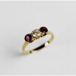 A ruby and diamond three-stone ring, comprising a central brilliant cut diamond weighing an